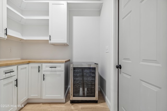 interior space with white cabinets, butcher block counters, wine cooler, and light hardwood / wood-style flooring