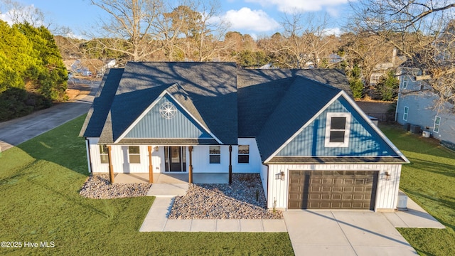 view of front of home with a garage, covered porch, and a front yard