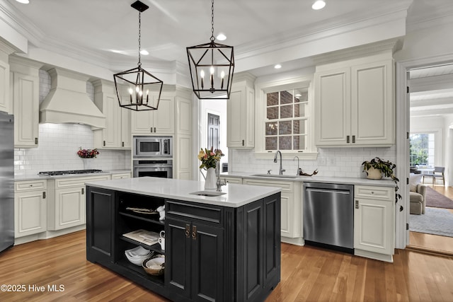 kitchen with stainless steel appliances, a center island, premium range hood, sink, and pendant lighting