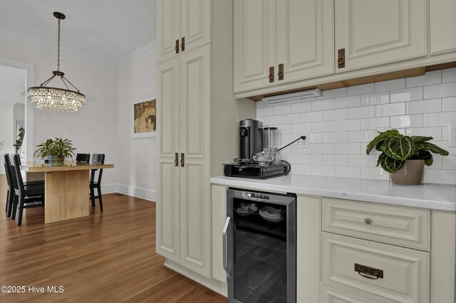 kitchen with hardwood / wood-style floors, backsplash, pendant lighting, wine cooler, and crown molding