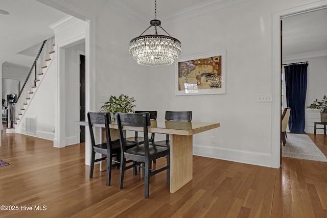 dining room with hardwood / wood-style flooring, crown molding, and an inviting chandelier