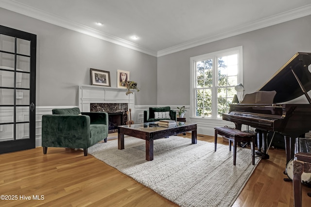 living area with hardwood / wood-style flooring, ornamental molding, and a high end fireplace