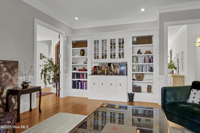 living area featuring hardwood / wood-style flooring, crown molding, and built in features