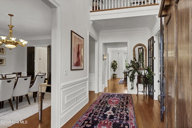 entrance foyer featuring crown molding, an inviting chandelier, and wood-type flooring