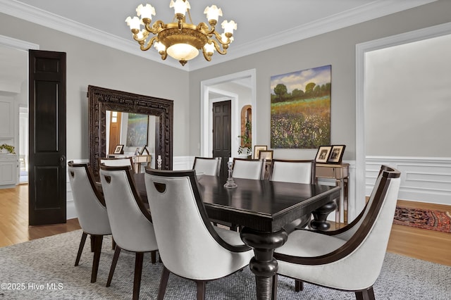 dining space featuring ornamental molding, a notable chandelier, and light hardwood / wood-style flooring