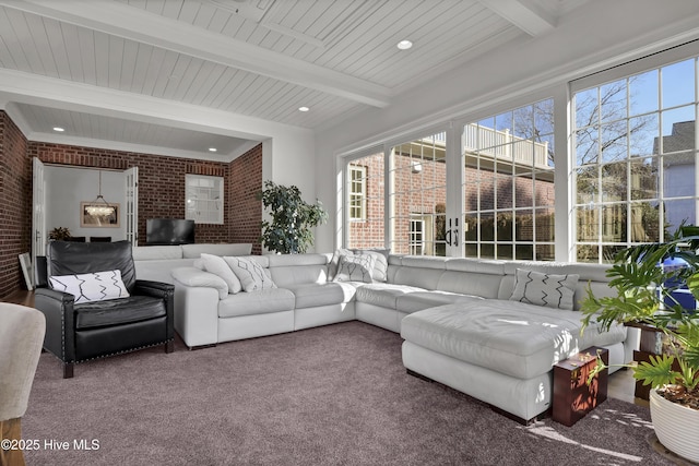 living room with beamed ceiling, brick wall, and carpet floors