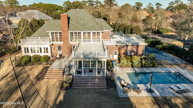 rear view of house featuring a balcony, a fenced in pool, and a patio area