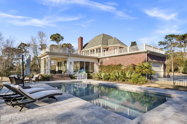 back of property with a fenced in pool, a patio, and a balcony