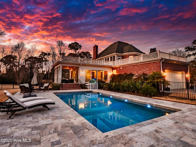 pool at dusk with a patio area