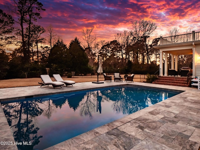 pool at dusk with a patio