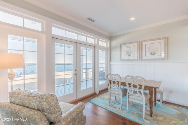 dining room featuring a water view, wood-type flooring, french doors, and a wealth of natural light