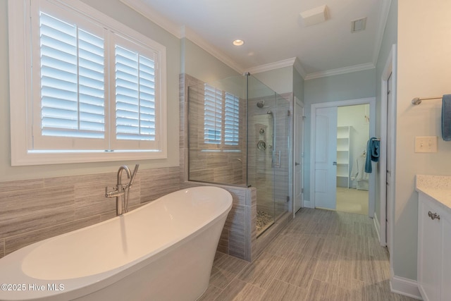 bathroom with vanity, shower with separate bathtub, tile walls, and crown molding