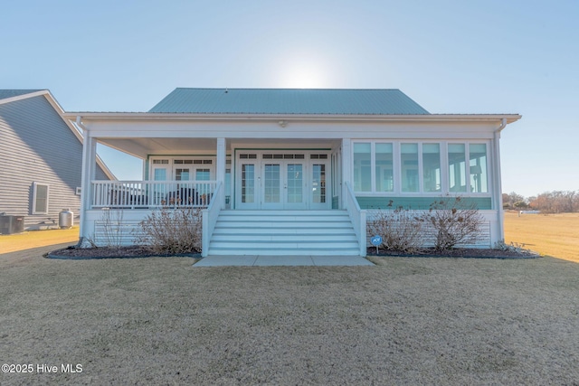 view of front facade with a front lawn, central air condition unit, and covered porch