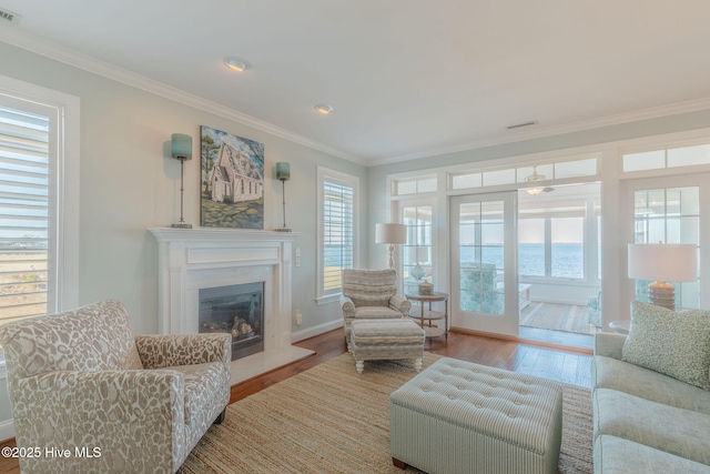 living room featuring a water view, ornamental molding, and light hardwood / wood-style flooring