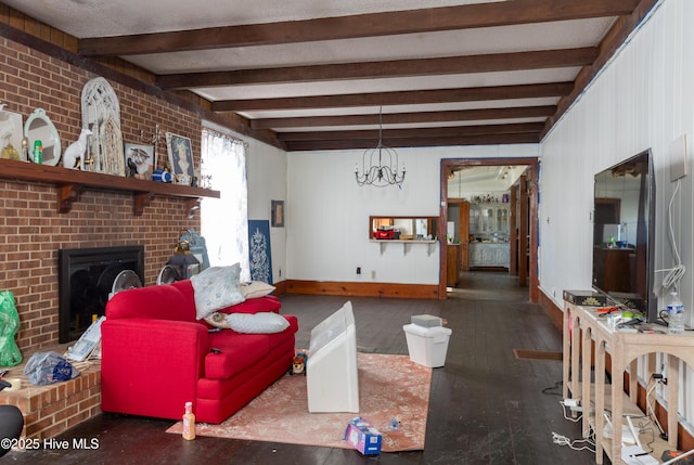 living room with a brick fireplace, a chandelier, beamed ceiling, and dark wood-type flooring