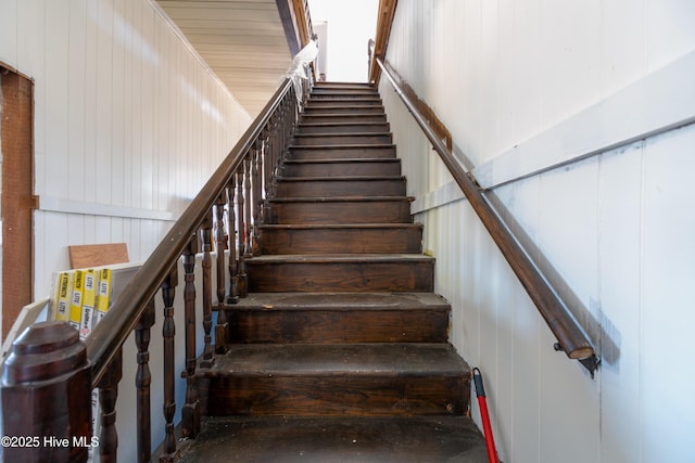 staircase featuring wood walls