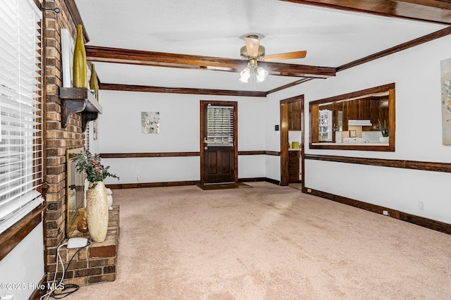 interior space featuring a fireplace, ceiling fan, crown molding, and carpet