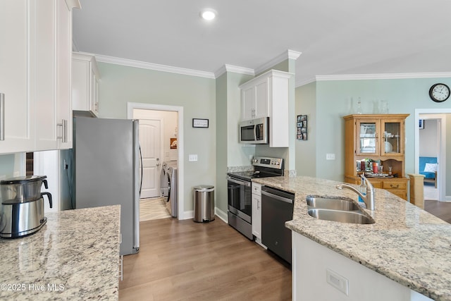 kitchen with light stone countertops, white cabinets, washer and dryer, appliances with stainless steel finishes, and sink