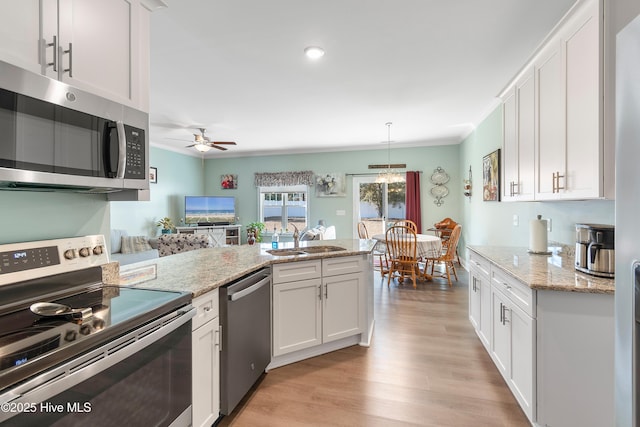 kitchen featuring sink, white cabinets, ceiling fan, light stone countertops, and appliances with stainless steel finishes