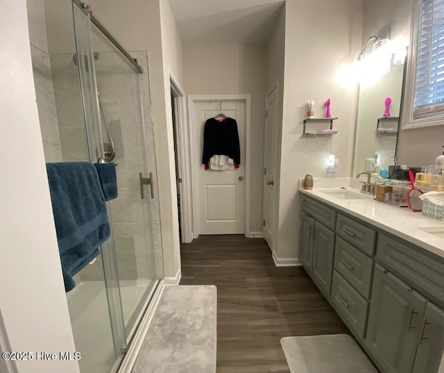 bathroom featuring hardwood / wood-style floors, a shower with door, and vanity