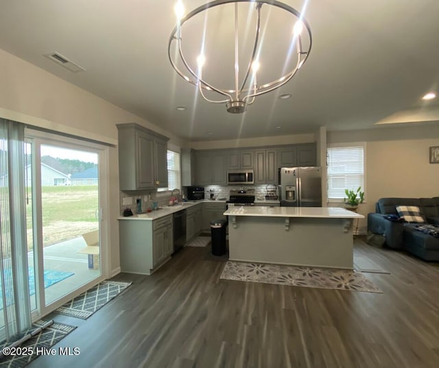 kitchen featuring a notable chandelier, gray cabinets, a center island, sink, and appliances with stainless steel finishes