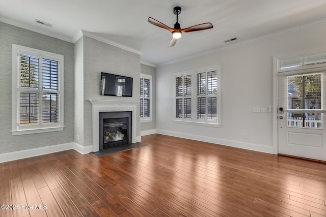 unfurnished living room with wood-type flooring, baseboards, crown molding, and a glass covered fireplace