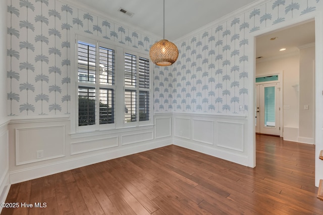 unfurnished dining area with hardwood / wood-style flooring, a wainscoted wall, and wallpapered walls