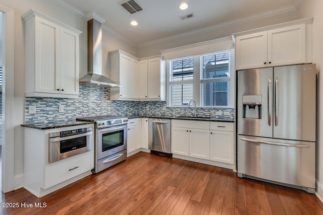 kitchen featuring stainless steel appliances, a sink, visible vents, wall chimney exhaust hood, and dark wood finished floors