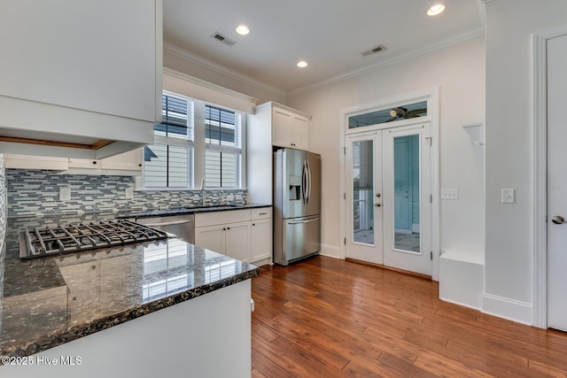 kitchen featuring stainless steel appliances, tasteful backsplash, white cabinetry, dark stone counters, and sink