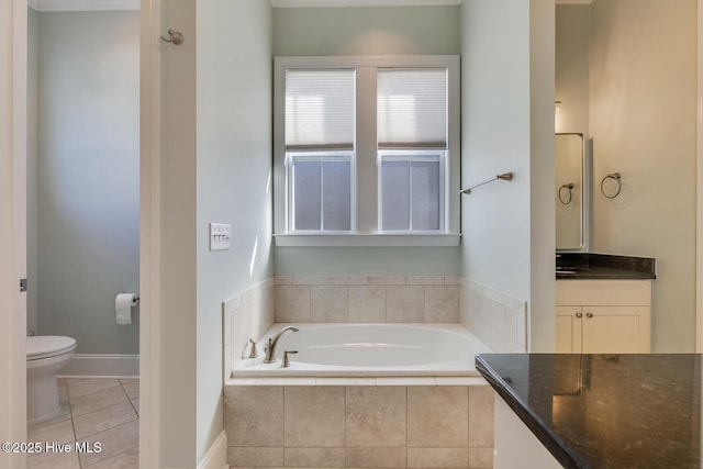 bathroom featuring tile patterned flooring, toilet, vanity, and tiled tub