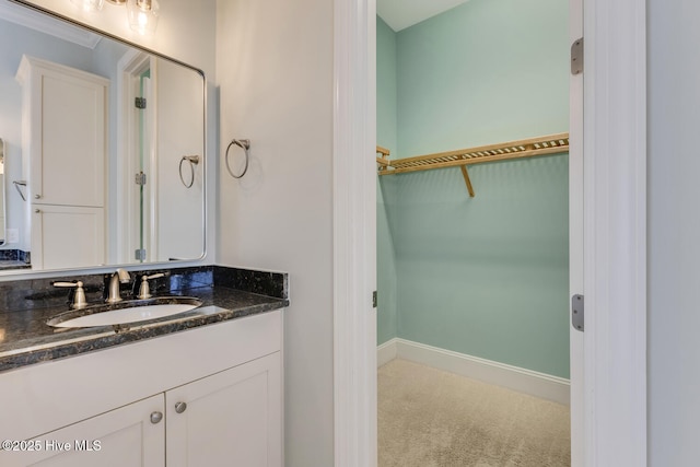 bathroom featuring baseboards, a spacious closet, and vanity