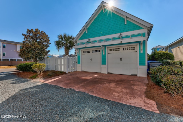 garage featuring concrete driveway and fence