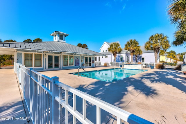 community pool featuring french doors, a patio area, and fence