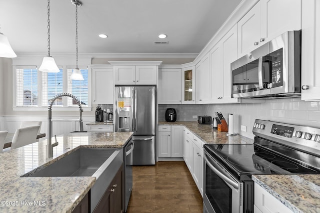 kitchen with stainless steel appliances, pendant lighting, and white cabinets