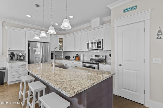 kitchen with stainless steel appliances, white cabinets, a center island with sink, and sink