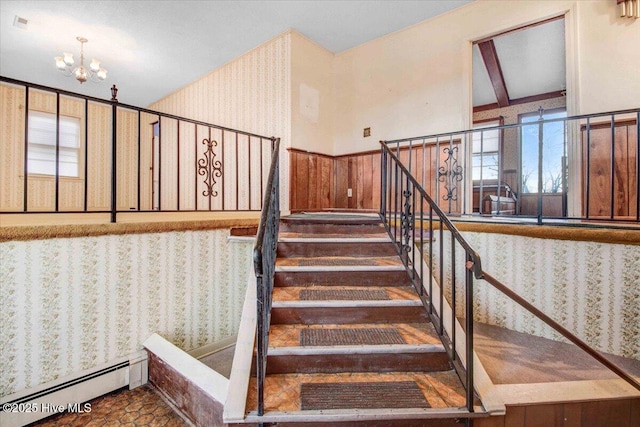 staircase featuring an inviting chandelier, a baseboard radiator, and wood walls