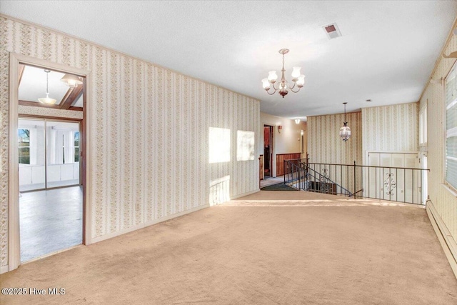 unfurnished room featuring a baseboard heating unit, an inviting chandelier, a textured ceiling, and carpet floors