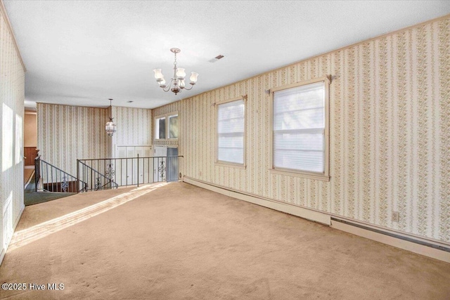 empty room featuring a baseboard heating unit, a notable chandelier, and carpet flooring