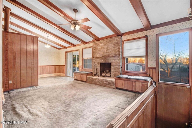 carpeted living room featuring ceiling fan, a brick fireplace, wooden walls, and lofted ceiling with beams