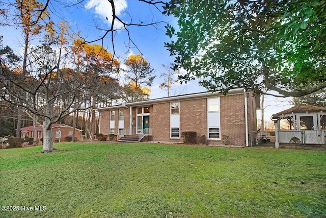 rear view of house with brick siding and a lawn