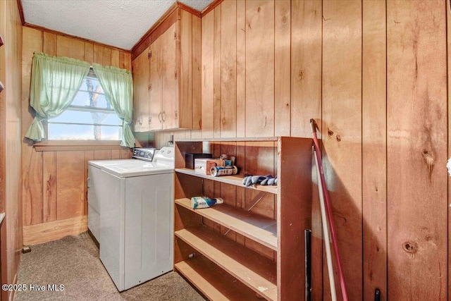 washroom with a textured ceiling, wooden walls, light carpet, and washing machine and clothes dryer