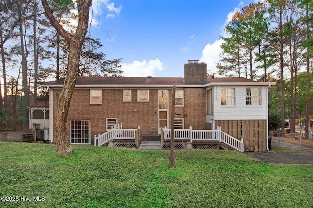 view of front of property with a wooden deck, a chimney, a front lawn, and brick siding