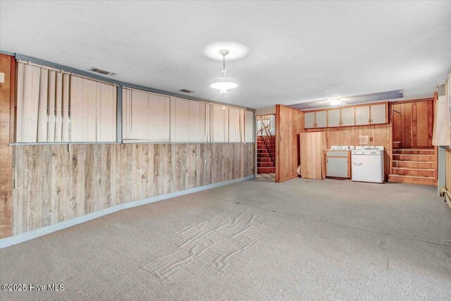 unfurnished living room with a baseboard heating unit, light colored carpet, and wood walls