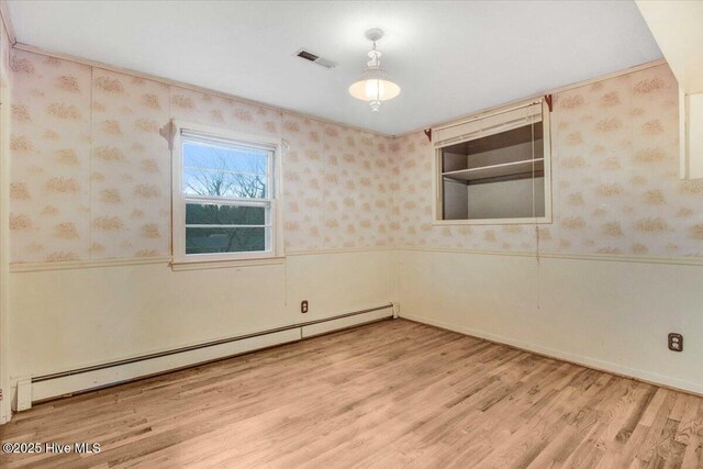 empty room featuring light hardwood / wood-style floors, baseboard heating, and ceiling fan