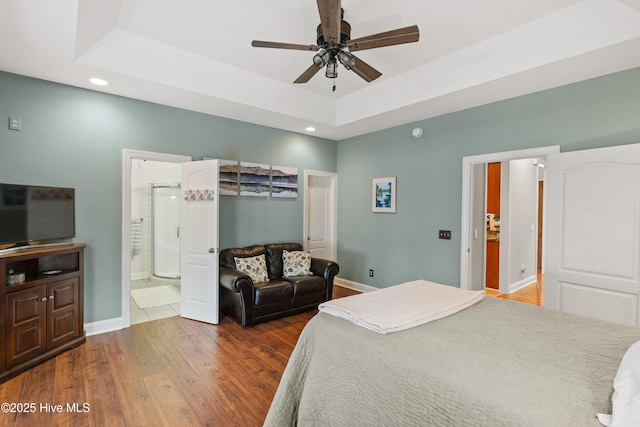 bedroom featuring ensuite bath, ceiling fan, hardwood / wood-style flooring, and a raised ceiling