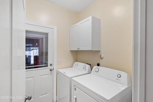 clothes washing area featuring washer and clothes dryer and cabinets