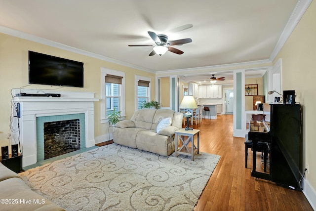 living room with hardwood / wood-style floors, ornamental molding, and ceiling fan