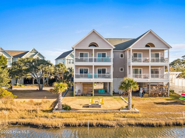 back of house featuring a yard, a balcony, and a water view