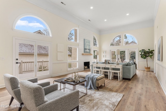 living room with a fireplace, light hardwood / wood-style flooring, and ornamental molding