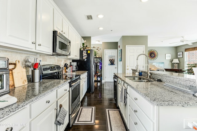 kitchen featuring white cabinets, appliances with stainless steel finishes, sink, backsplash, and light stone counters